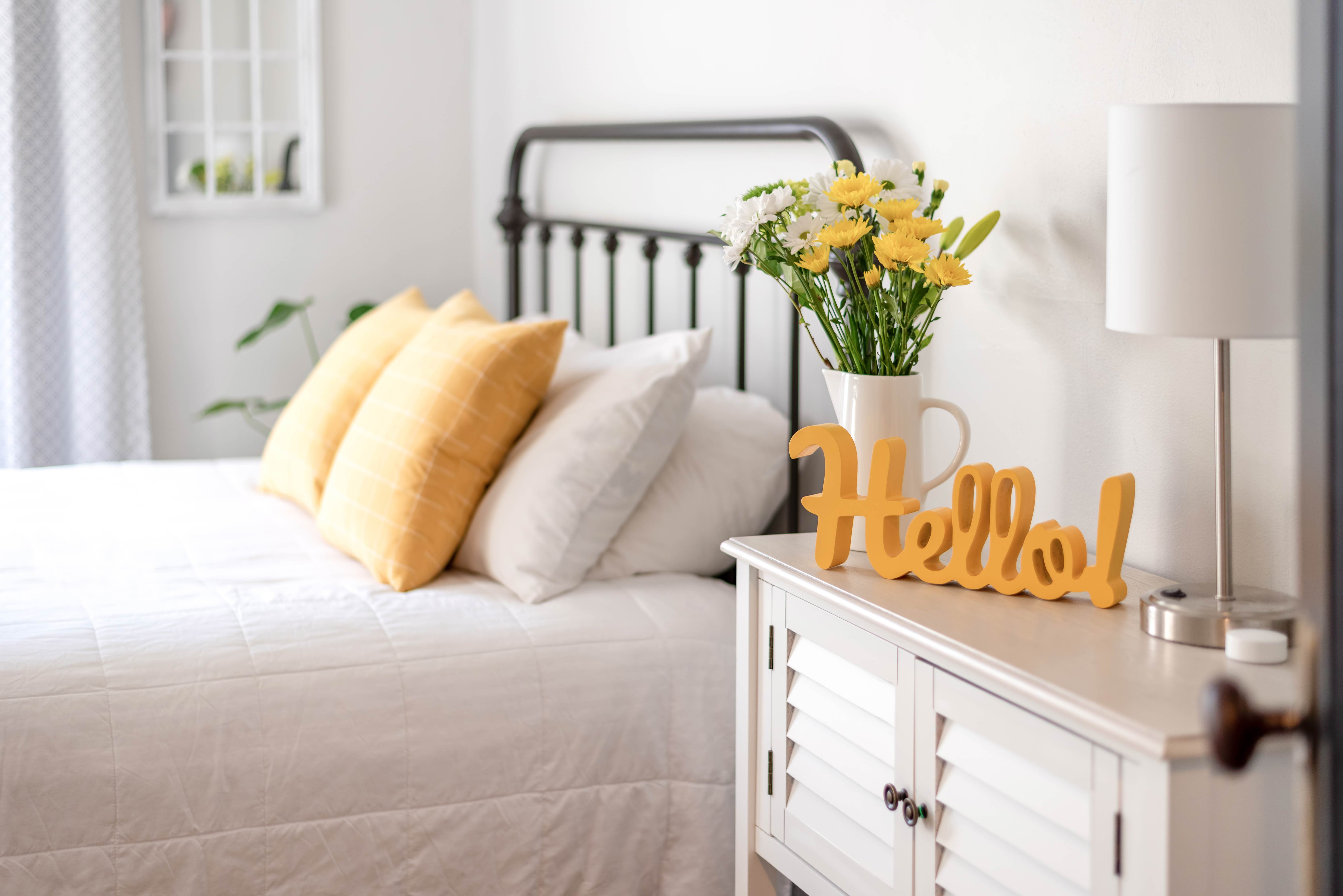 Cheerful-hello-sign-in-clean-and-bright-bedroom-with-yellow-accents
